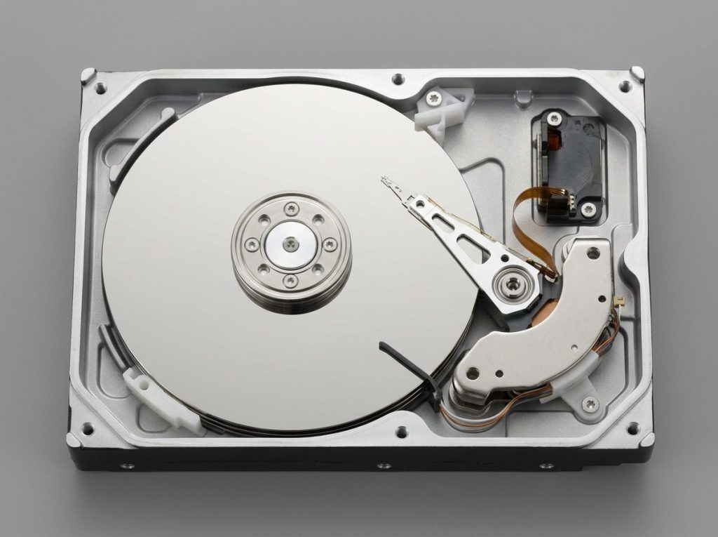 Cutaway of a hard drive showing platter, actuator arm and read/write heads parked on the ramp, the parts behind clicking