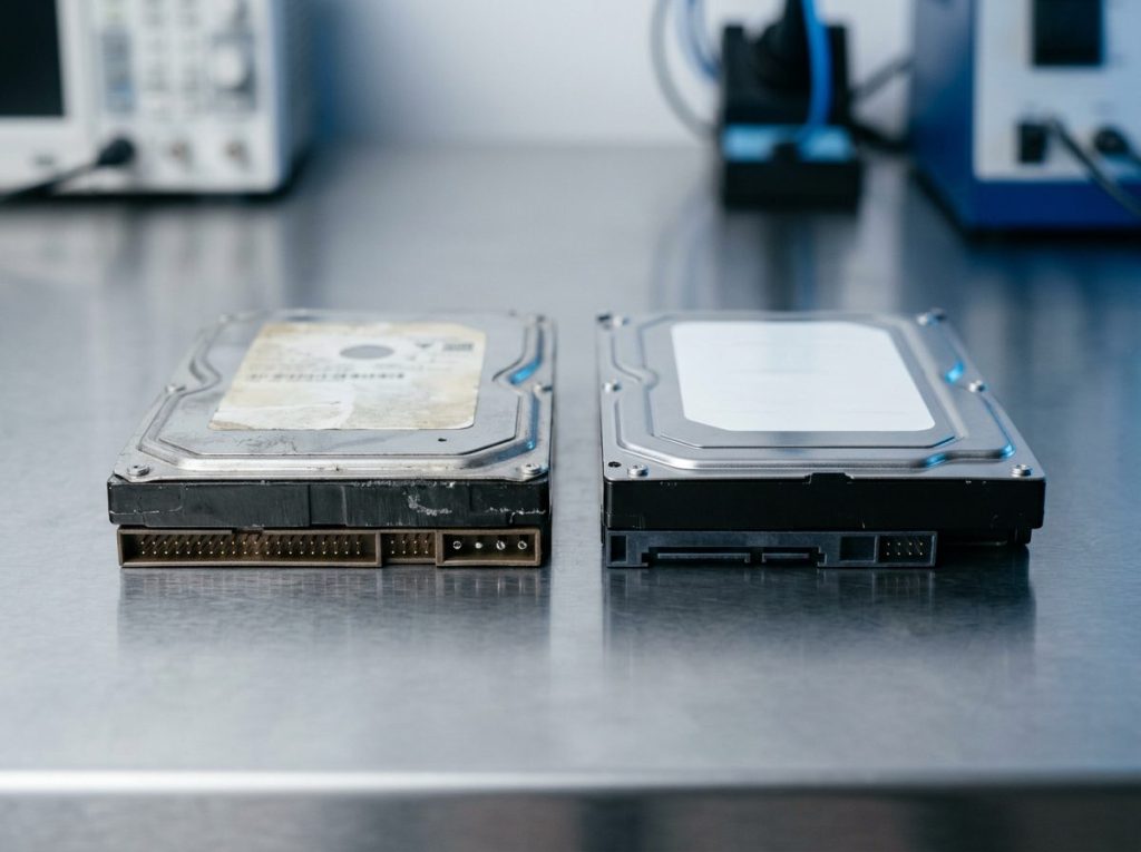 Old failed 3.5-inch hard drive next to a new replacement disk used to rebuild a CNC control computer