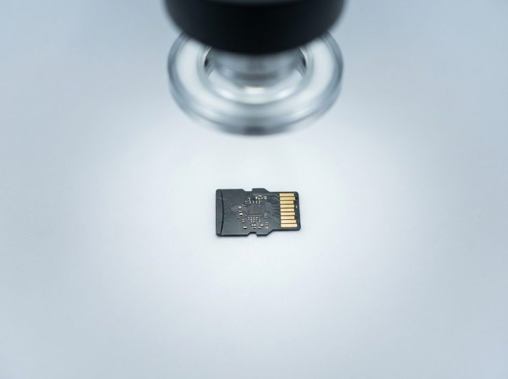 Monolith microSD card under an inspection microscope, contacts visible, prepared for direct memory reading